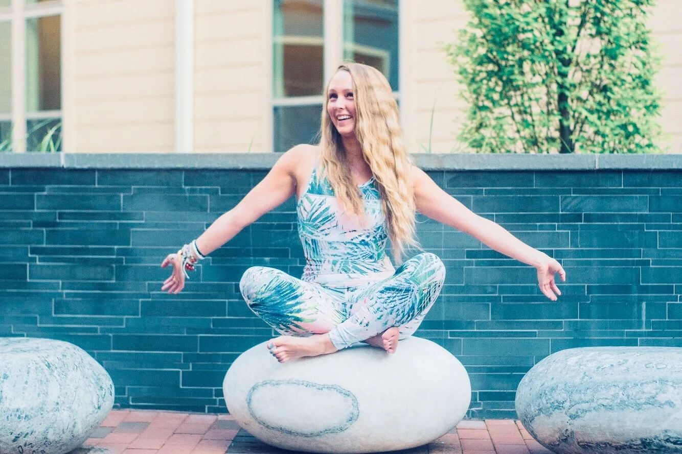 Maelis sitting cross-legged on a stone sphere