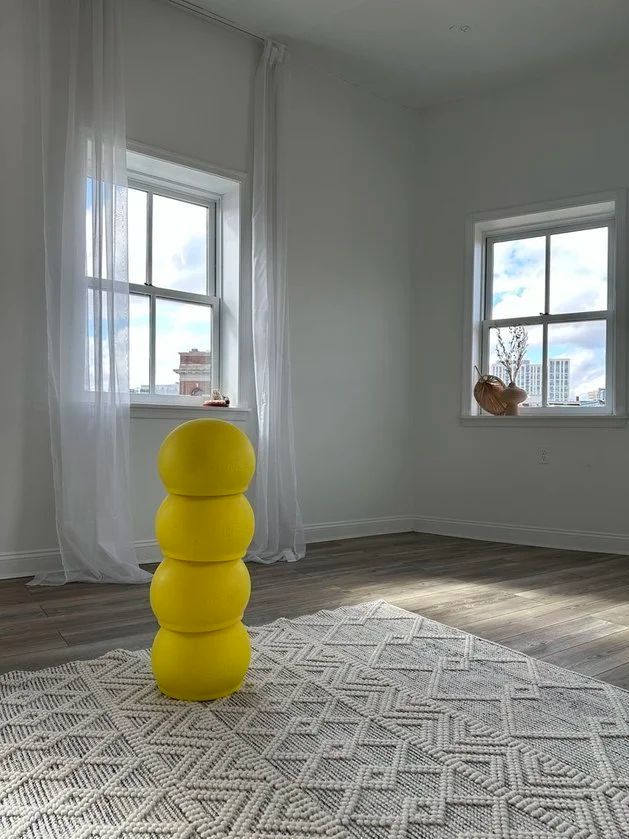 A stack of yellow BOUNCE balls in a bright room